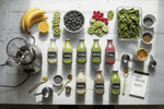 flat-lay-of-a-weekly-smoothie-prep-routine-with-labeled-glass-bottles-fresh-fruits-leafy-greens-seeds-blender