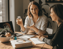 a nutritionist or health coach holding a clear glass bottle of liquid vitamins while explaining benefits to a client at a wooden table
